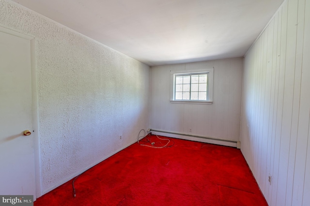 carpeted spare room featuring a textured wall and baseboard heating