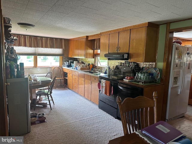 kitchen with brown cabinets, light carpet, white refrigerator with ice dispenser, black range with electric cooktop, and under cabinet range hood