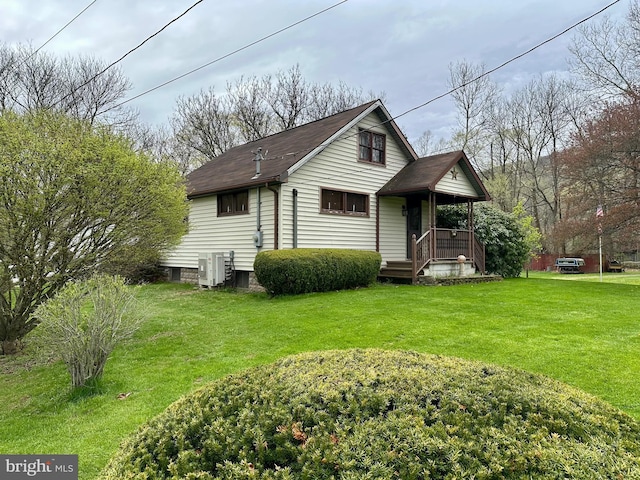 rear view of house featuring a lawn, a shingled roof, and ac unit