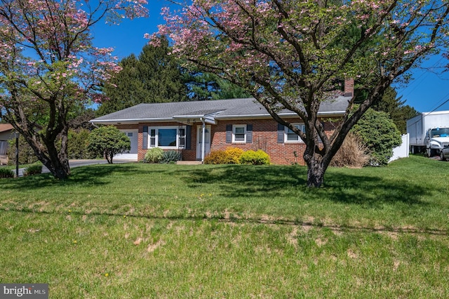 ranch-style home featuring brick siding, a chimney, and a front yard