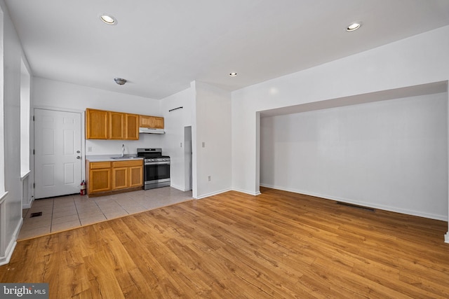 3800 Spring Garden St, Philadelphia, PA 19104 - kitchen featuring stainless steel gas range, a sink, light wood-style floors, light countertops, and under cabinet range hood