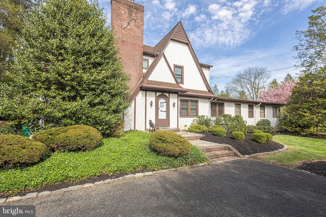 tudor house featuring stucco siding and a chimney