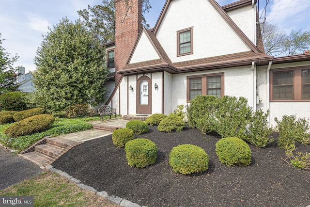 tudor house with stucco siding and a chimney