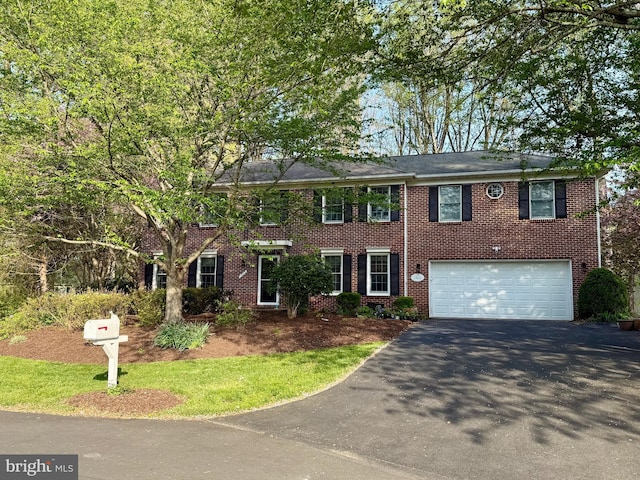colonial-style house featuring brick siding, a garage, and driveway