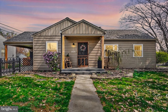 bungalow-style home featuring fence, board and batten siding, a shingled roof, and a front yard