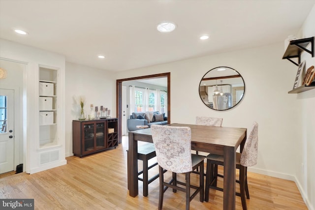 dining space with recessed lighting, visible vents, built in shelves, and light wood finished floors