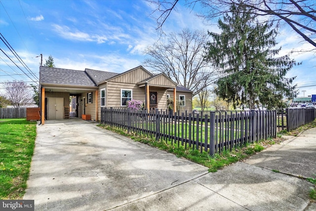 single story home featuring concrete driveway, a carport, a fenced front yard, and a front lawn