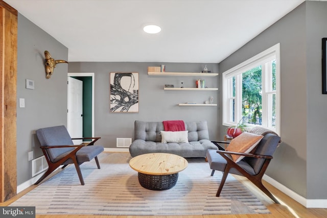sitting room featuring baseboards, visible vents, and wood finished floors
