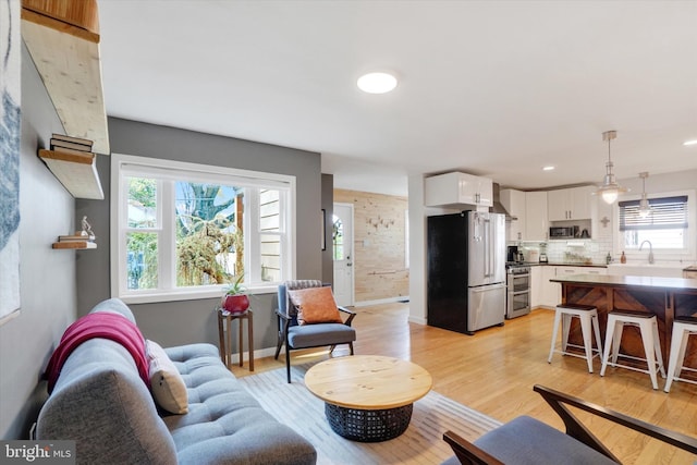 living area featuring recessed lighting, light wood finished floors, and baseboards