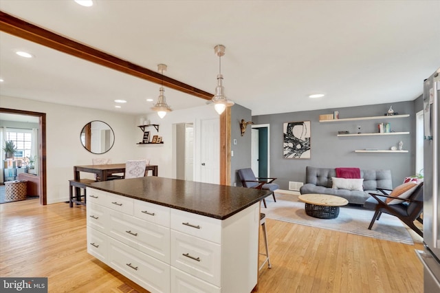 kitchen with a kitchen island, dark countertops, light wood finished floors, recessed lighting, and white cabinetry