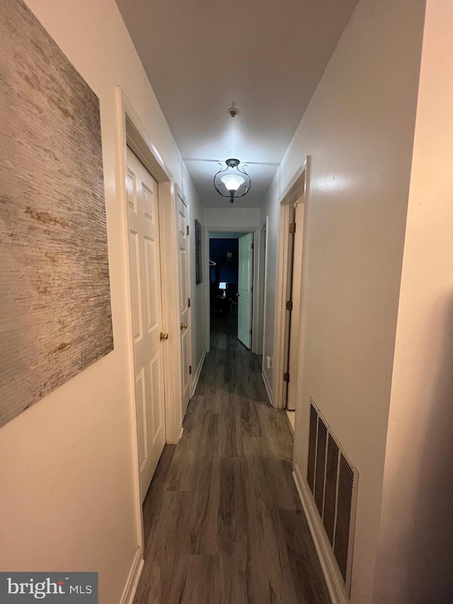 hallway with dark wood finished floors and visible vents