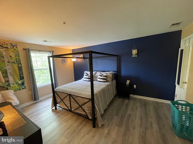 bedroom featuring baseboards, visible vents, and wood finished floors