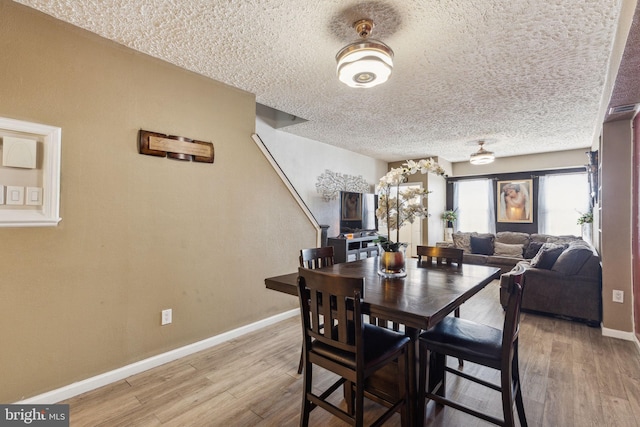dining room featuring baseboards, a textured ceiling, and wood finished floors