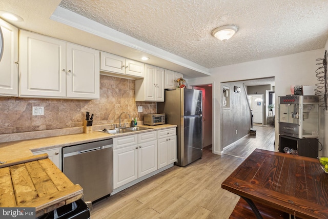 kitchen featuring light countertops, stainless steel appliances, a textured ceiling, and a sink