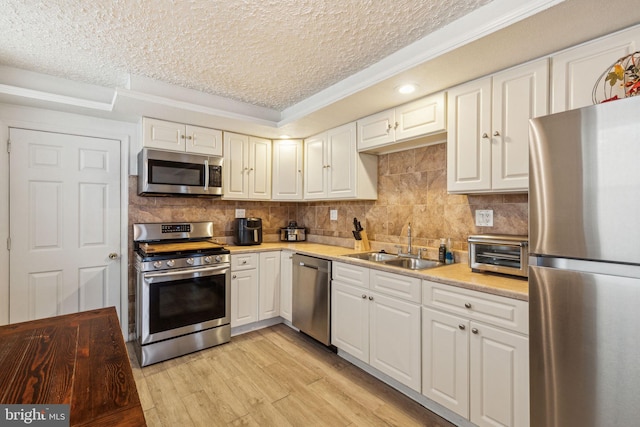 kitchen featuring a textured ceiling, a sink, light countertops, a toaster, and stainless steel appliances