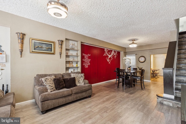 living area featuring baseboards, a textured ceiling, and wood finished floors