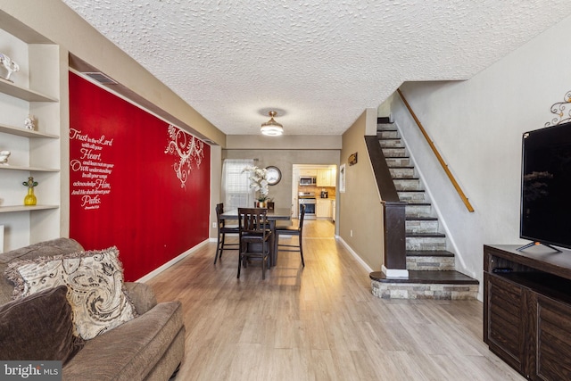 dining space with a textured ceiling, stairs, wood finished floors, and visible vents