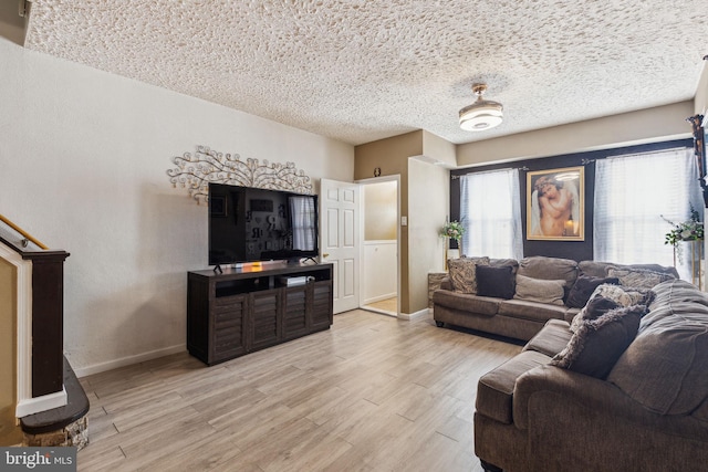 living area featuring a textured ceiling, baseboards, and light wood-style flooring