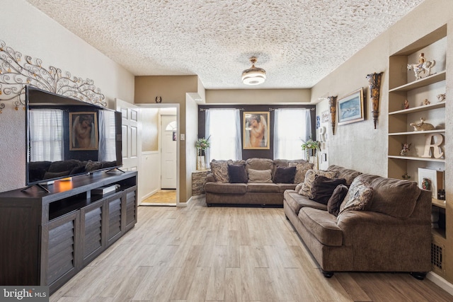 living room featuring light wood-type flooring, a textured ceiling, and visible vents
