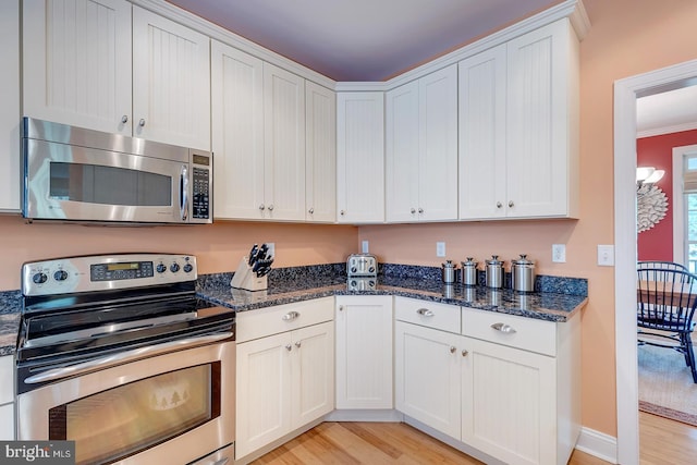 22758 Red Bay Ln, Milton, DE 19968 - kitchen featuring stainless steel appliances, light wood-style flooring, dark stone countertops, and white cabinetry