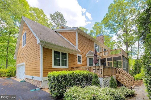 22758 Red Bay Ln, Milton, DE 19968 - rear view of property featuring a chimney, a deck, roof with shingles, a sunroom, and stairs