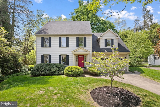 colonial house with concrete driveway, a front yard, and a garage
