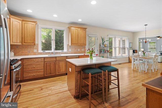 kitchen featuring appliances with stainless steel finishes, plenty of natural light, a sink, and a kitchen bar