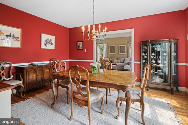 dining area with baseboards, an inviting chandelier, and wood finished floors