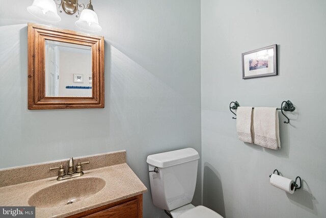 half bathroom featuring vanity, toilet, and a notable chandelier