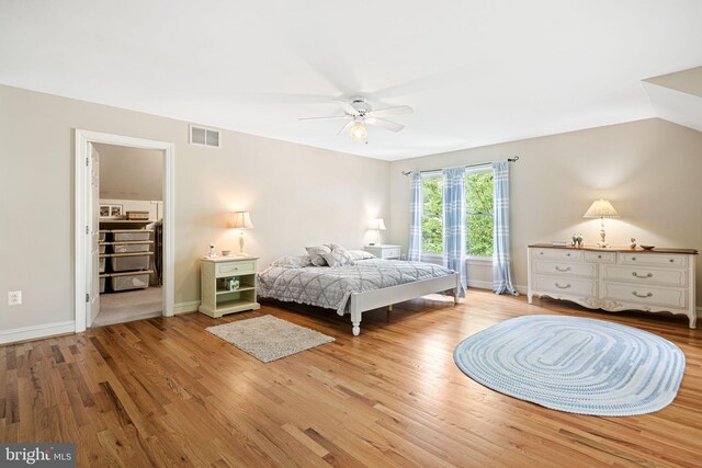 bedroom with a ceiling fan, baseboards, wood finished floors, a spacious closet, and visible vents