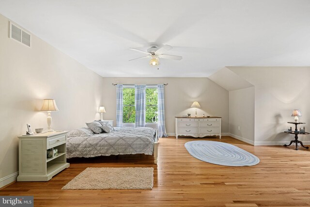 bedroom featuring a ceiling fan, visible vents, wood finished floors, baseboards, and lofted ceiling