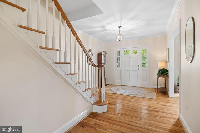 entrance foyer with stairway, baseboards, wood finished floors, and a chandelier