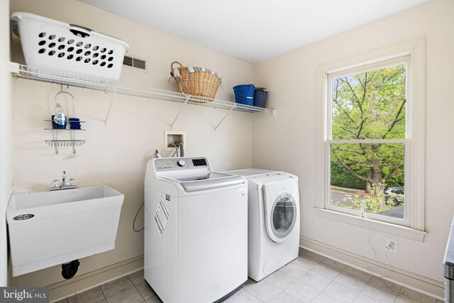 washroom with independent washer and dryer, laundry area, baseboards, and a sink
