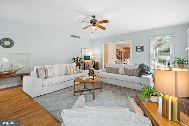living area featuring baseboards, a ceiling fan, wood finished floors, and visible vents