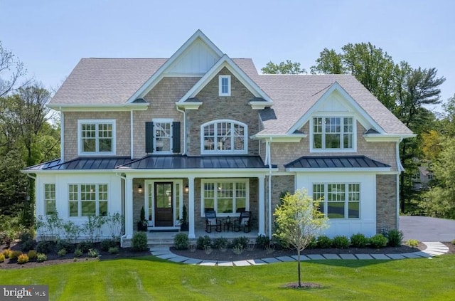 view of front of property featuring a front lawn, roof with shingles, covered porch, and a standing seam roof