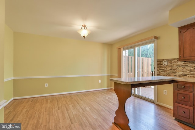 1514 Ravena St Unit D, Bethlehem, PA 18015 - kitchen featuring decorative backsplash, brown cabinetry, light countertops, baseboards, and light wood-style flooring