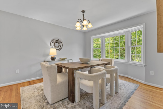 dining room with an inviting chandelier, baseboards, and light wood-style flooring