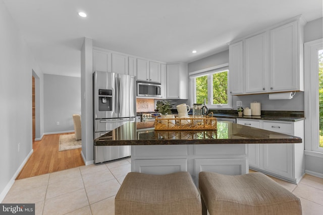 kitchen featuring a kitchen island, baseboards, recessed lighting, white cabinetry, and appliances with stainless steel finishes