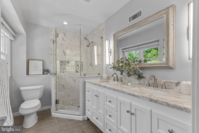 bathroom featuring toilet, visible vents, a marble finish shower, and a sink