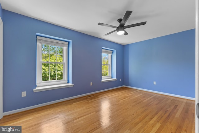 unfurnished room featuring baseboards, visible vents, and wood finished floors