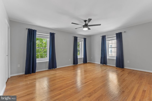 unfurnished room with baseboards, ceiling fan, a wealth of natural light, and light wood-type flooring