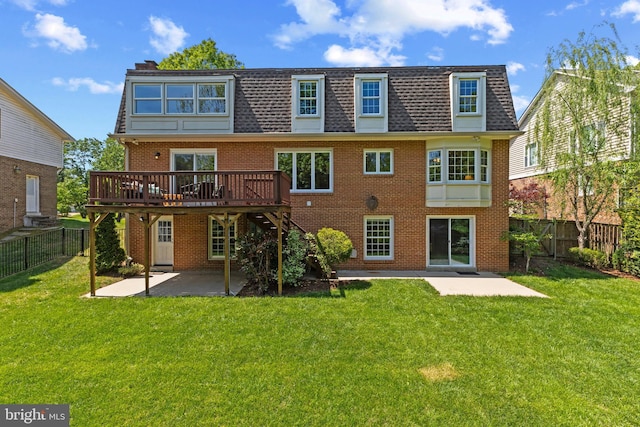 rear view of house with a patio, a wooden deck, mansard roof, and brick siding