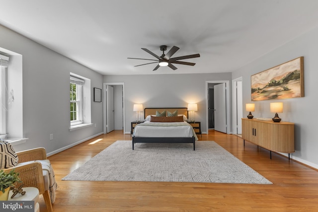 bedroom with baseboards, a ceiling fan, and light wood-style flooring