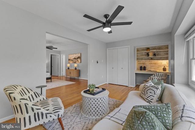living room with baseboards, ceiling fan, and wood finished floors