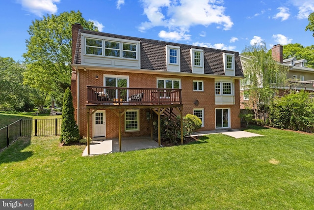back of house featuring a lawn, a wooden deck, brick siding, a fenced backyard, and a patio