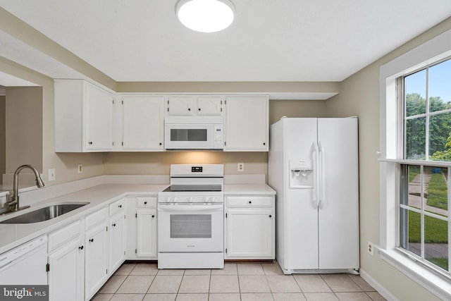 kitchen featuring white appliances, a sink, light tile patterned floors, white cabinetry, and light countertops