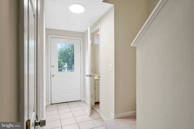 doorway with light tile patterned floors and baseboards