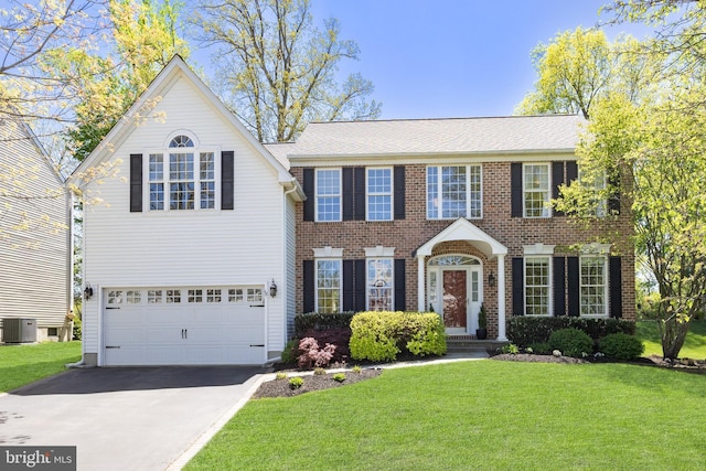 colonial home featuring an attached garage, concrete driveway, central AC, and a front yard