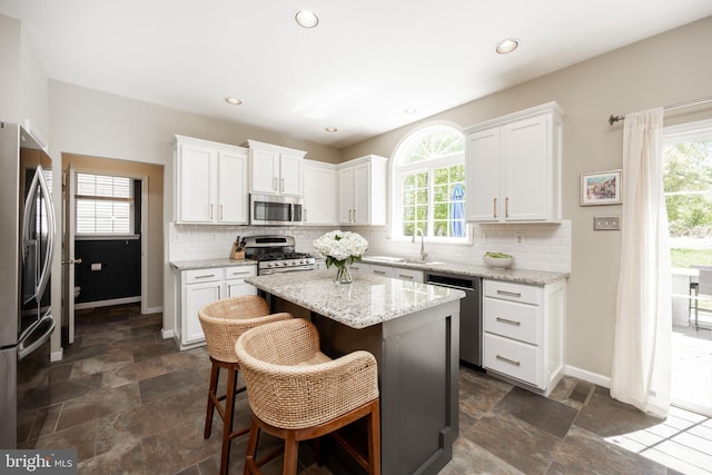 kitchen featuring backsplash, white cabinetry, baseboards, and appliances with stainless steel finishes