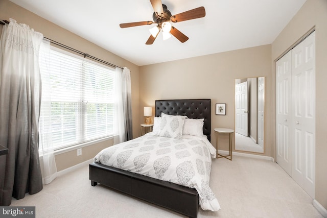 bedroom featuring baseboards, a ceiling fan, a closet, and light colored carpet
